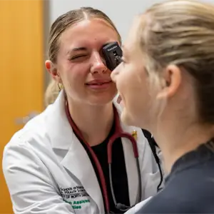 Female student looking to the eye of a patient