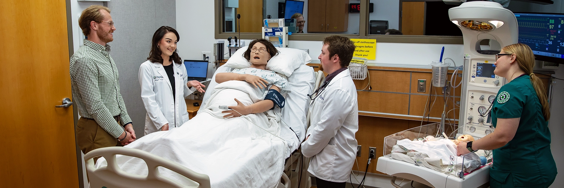Students in white coats talking in SMHS Simulation Center